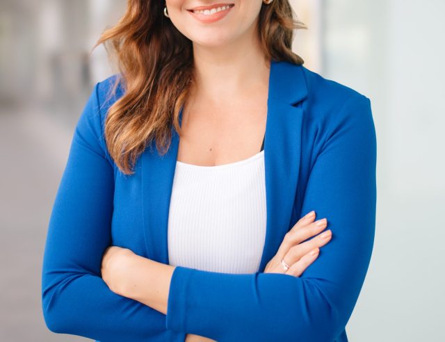Professional portrait of Rebecca Kennedy smiling with crossed arms, wearing a blue blazer and white top.