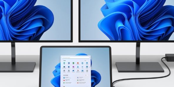 Workspace with two large monitors and a connected tablet or laptop displaying the Windows 11 start menu – including keyboard, numeric keypad, and mouse. Symbolic image for modern IT workstations and Windows environments.