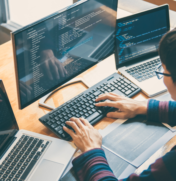 Developer programming on multiple computer screens.