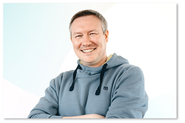 Oliver Ganswig wearing a light blue sweater in front of a light blue and white background.