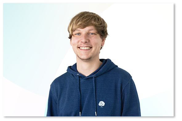 Sebastian Lutz in a dark blue sweater in front of a light blue and white background.